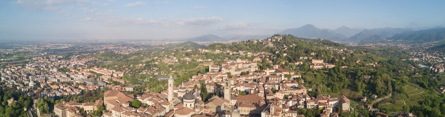 Fototapeta premium Drone aerial view of Bergamo - Old city (upper town), Italy. Landscape on the city center, the old fortress and its historical buildings during a wonderful blu day