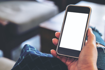 Mockup image of hands holding black mobile phone with blank white screen in the cafe