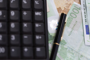euro notes with a pen and a calculator machine 