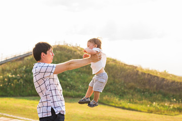 Happy child, dad and son having fun, holding on hands on a sunlight sunset background. Family, travel, vacation, childhood, father's day - concept