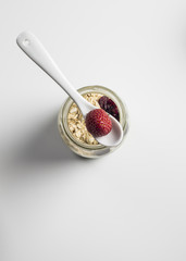 Healthy breakfast - Fresh homemade granola, berries and y yogurt in a glass jar on a white wooden background, selective focus