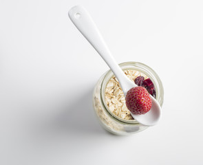 Healthy breakfast - Fresh homemade granola, berries and y yogurt in a glass jar on a white wooden background, selective focus