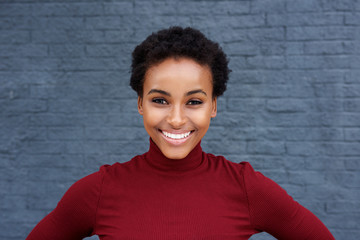 Close up beautiful young black woman smiling against gray wall