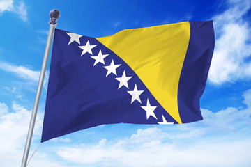 Flag of Bosnia and Herzegovina developing against a clear blue sky