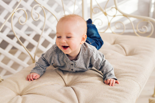 Adorable laughing baby boy in sunny bedroom. Newborn child relaxing. Nursery for young children.Family morning at home. Little kid lying on tummy