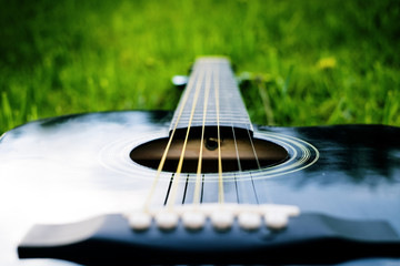 Detail of acoustic guitar on a grass. Natural background with flowers, grass and sun. Musical...