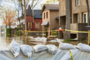 Close shot of flood Protection Sandbags with flooded homes in the background