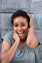 Naklejka premium beautiful young black woman laughing with hands to face