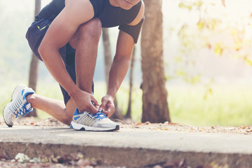 Man tying jogging shoes.A person running outdoors on a sunny
