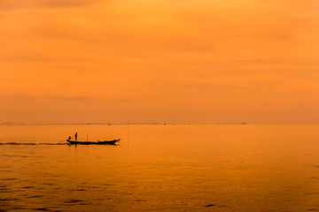 Asian fisherman on wooden boat with sunset time,Beautiful sunrise and silhouette of fishing boat.
