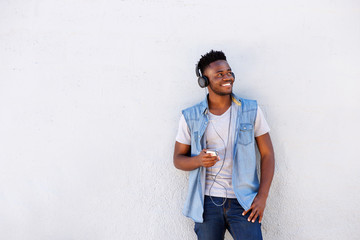 cool african guy with mobile phone and headphones listening to music