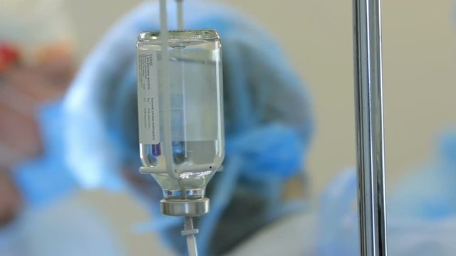 Nurse installs bottle of medicine to a dropper close up with a PAN