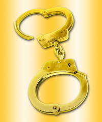 Golden handcuffs - isolated against a gold background.