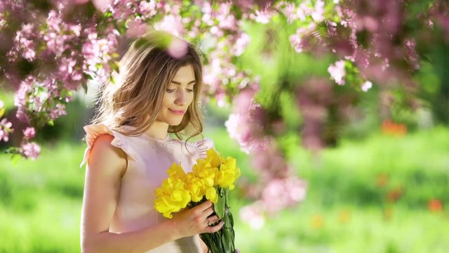 Pretty woman with bouquet of tulips at flowered garden