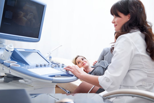 Shot of a cheerful female gynecologist performing ultrasound scanning on her pregnant patient profession occupation medicine job healthcare pregnancy fertility gynecology expecting unborn children.