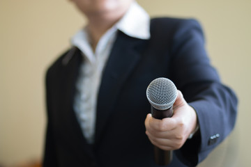 blurred of businesswoman speech and reporter with microphone at presentation in conference