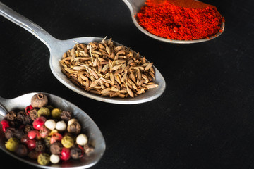spoons with salt and spices on black chalkboard