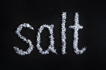 text salt poured in large sea salt on black