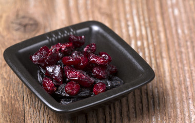 Dried Black and Red berries in a black plate on wooden background