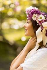 Obraz premium Young woman with flowers in her hair on sunny spring day
