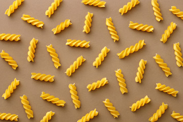 Top view of spiralli pasta pattern.Flat lay raw spilled Italian pasta view from above on neutral...