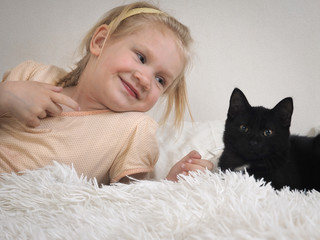 Happy little girl with a kitten on the bed