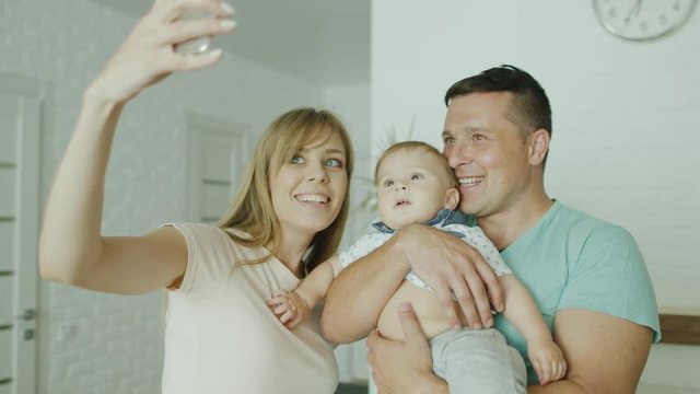 A young couple parent makes a selfie along with her baby boy. In his new bright home. Concept - housewarming, happy family with a child