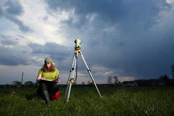 Женщина геодезист делает замеры