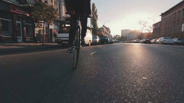 Cyclist man riding fixed gear sport bike in sunny day on a city at sunset