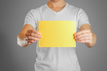 A man holds a yellow paper in his hand. Shows a blank flyer. Isolated
