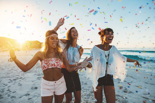 Female friends partying on the beach with confetti