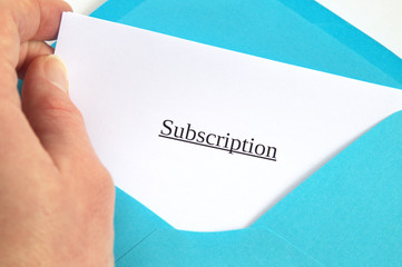Subscription printed on white paper and blue envelope, hand holding it, white background