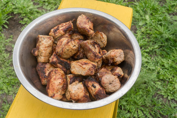 Pieces of tasty pork meat fried on a grill waiting to be eaten in a metal bowl