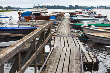 Fototapeta na wymiar Old wooden floating pier with moored boats