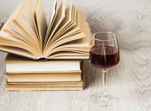 A glass of red wine and books on the table. The concept of rest