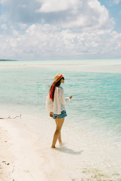 Woman walking along beach, looking at view, Tahiti, South Pacific