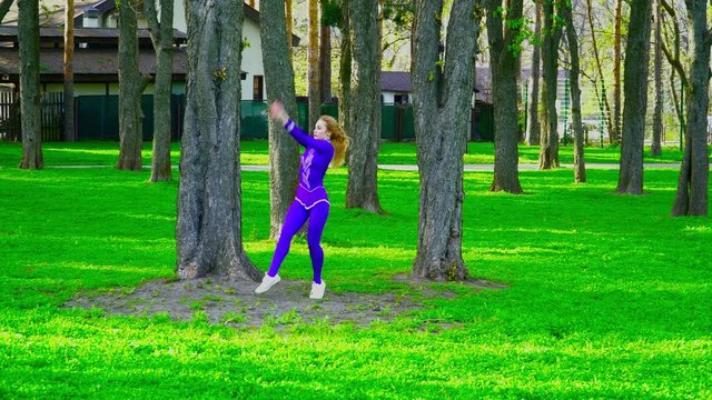 Young beautiful gymnast dacing and making tricks in the park