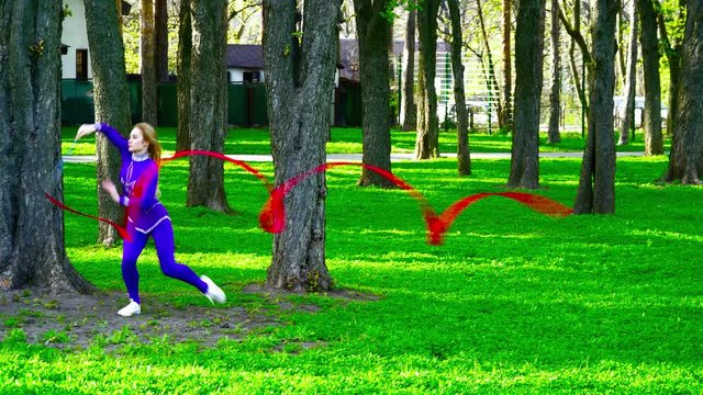 Young gymnast dacing with the ribbon in the park