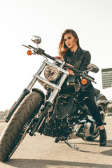 Fototapeta na wymiar Girl on a motorcycle. She is beautiful, posing on a motorcycle at sunset