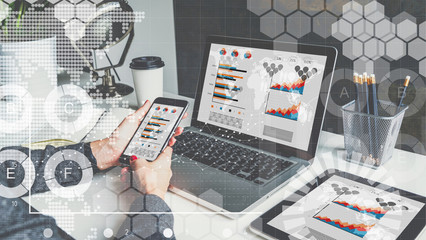 On table are laptop,digital tablet with charts,graphics and diagrams on screens.