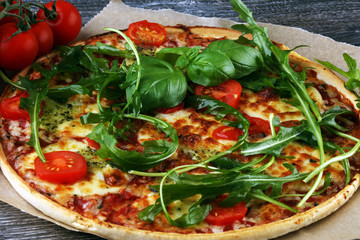 Hot true ITALIAN PIZZA with basil, arugula and cheese. TOP VIEW Tasty traditional pepperoni pizza on board on wooden table with decoration