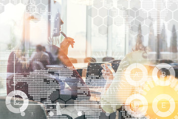 View through the glass. Back view. Silhouettes of two young women sitting in an office at a table and working