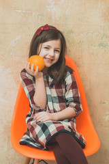 Happy girl with cute smile and orange in hand smiling