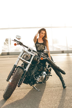Girl on a motorcycle. She is beautiful, posing on a motorcycle at sunset