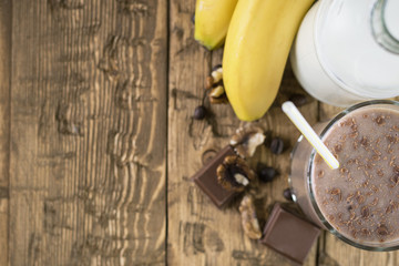 A bottle of milk and chocolate smoothies on a rustic table top view.