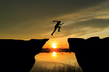 Man jumping over cliff on sunset background,Business concept idea