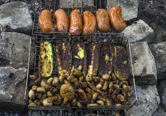 Eggplants, mushrooms and sausages cooked on the grill in the open air