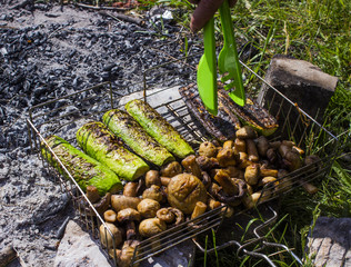 Eggplants and mushrooms cooked on fire, turns the guy with forceps