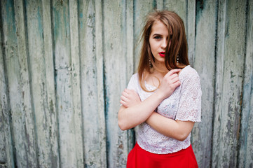 Fototapeta premium Portrait of beautiful girl with red lips against wooden background, wear on red dress and white blouse.