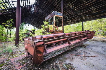 Fototapeta na wymiar Abandoned combine vehicle in collective farm near Zymovyshche ghost village in Chernobyl Exclusion Zone, Ukraine